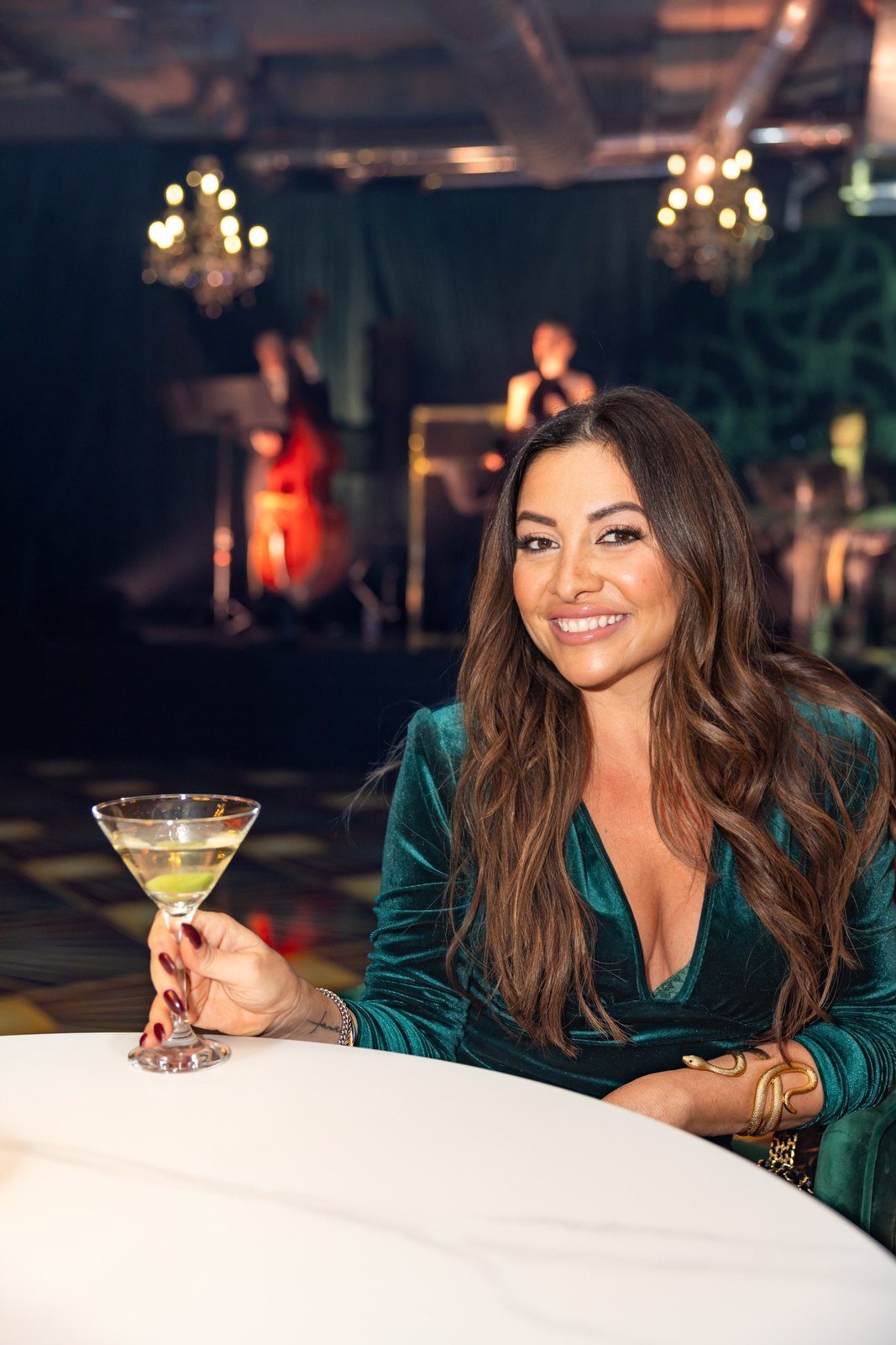 Maddy K seated at a table, green velvet