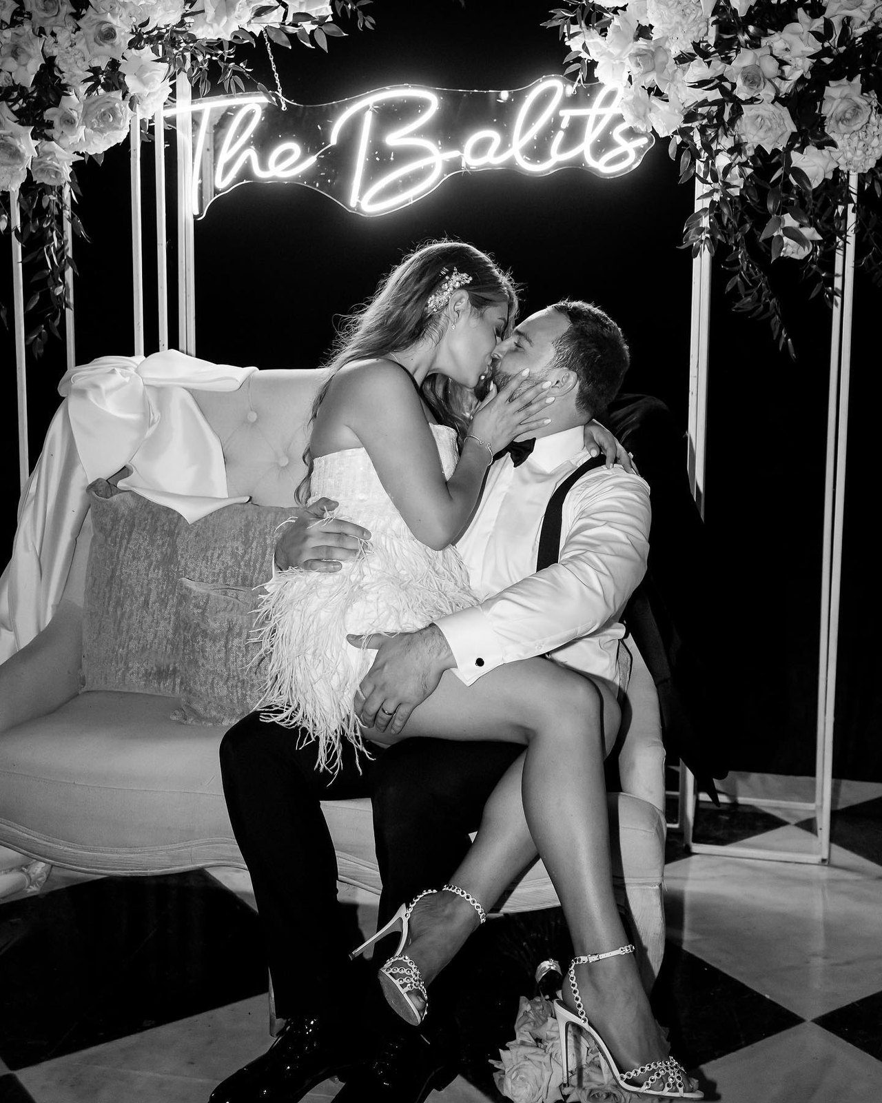 A couple beneath a neon sign, in black and white